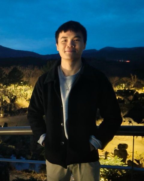 Gabriel Wan standing at a railing at dusk, with hills behind